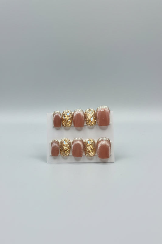 A set of handmade press-on nails displayed on a white card labeled 'Dream Styles HANDMADE NAILS.' The nails have a glossy nude-pink base with alternating clear rhinestone-covered and gold-glittered sections.